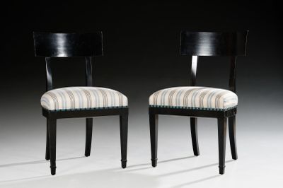 pair of black chairs with striped upholstered seats against a black background