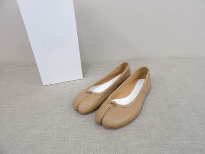 une paire de chaussures beiges posée sur une boîte blanche