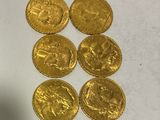six gold coins sitting on top of a table next to a bottle