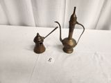 two antique brass teapots on a table with a white table cloth