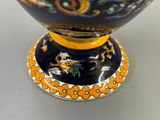 un vase bleu avec un socle jaune et un dragon représenté dessus