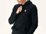 Cet homme porte un sweat à capuche noir et un pantalon beige.