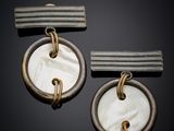two pieces of silver and mother of pearl earrings on a black background