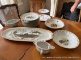 many plates and bowls on a table with a man standing in the background