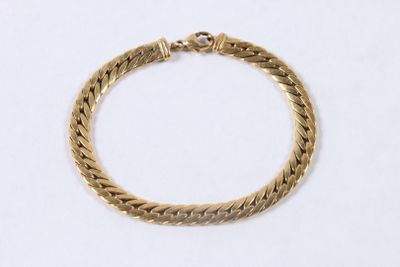 gros plan d'un bracelet en or sur une surface blanche
