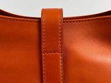 a close up of a brown leather bag with a leather strap