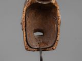 a close up of a wooden mask on a metal stand