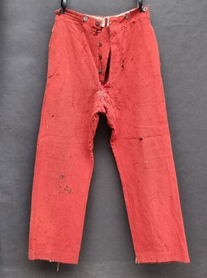 un vieux pantalon rouge suspendu à un porte-vêtements