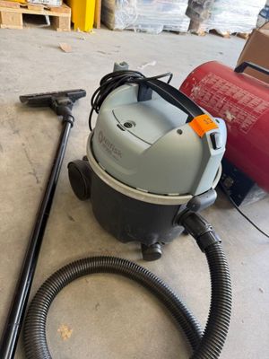 un aspirateur posé par terre à côté d'un bidon rouge