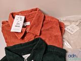 three shirts that are sitting on a table with a price tag