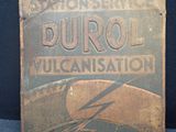 une vieille enseigne métallique annonçant la vulcanisation Durol sur fond bleu