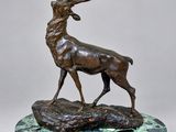 une statue en bronze représentant un cerf, posée sur un socle en marbre