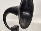 un vieux gramophone noir posé sur une surface blanche, avec un fond blanc