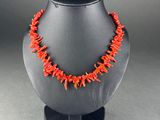 a necklace made of coral coral beads on a black mannequin