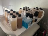 many bottles of liquid sitting on a shelf in a bathroom