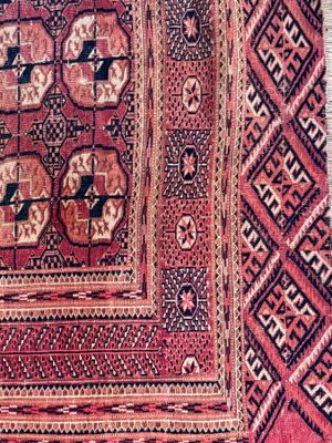 a close up of a red and black rug on a wooden floor
