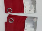 two pairs of red pants with silver rings on them sitting on a white surface