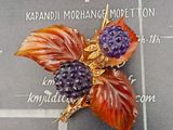 une photo d'une broche ornée d'une baie violette