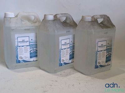 trois gallons de liquide posés les uns à côté des autres sur une table