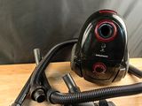 un aspirateur noir et rouge posé sur une table en bois
