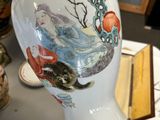 a white vase with a painting on it sitting on a table