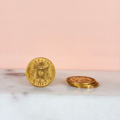 two gold coins sitting next to each other on top of a marble counter