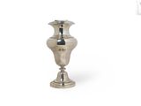 un vase en argent posé sur une surface blanche