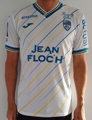 un homme debout, vêtu d'un maillot de foot