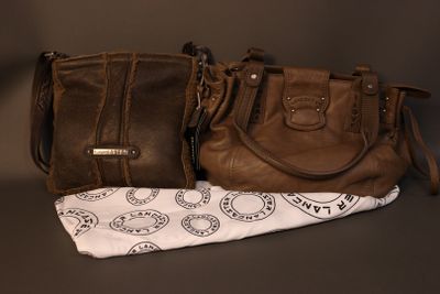two brown purses sitting next to each other on top of a table