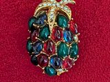 an image of a brooch with multi colored stones on a red surface
