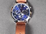wrist watch with blue dial and brown leather strap on grey surface