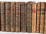 many old books lined up in a row on a shelf