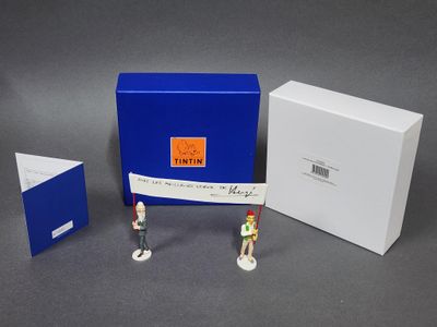 trois figurines représentant des personnes debout devant une boîte bleue et une boîte blanche