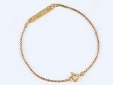 a gold chain bracelet with a heart charm on a white background