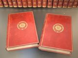 two red books sitting on top of a table next to a row of books