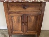 une armoire en bois avec un plateau en marbre, posée sur un sol en ciment
