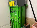a green machine that is next to some bottles of soda