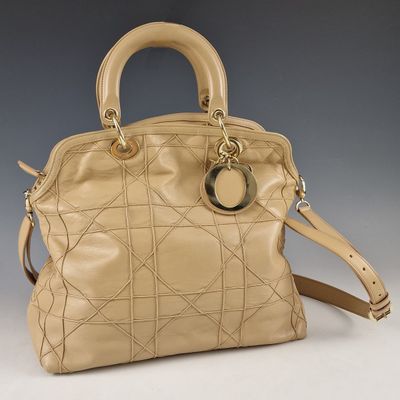 sac à main en cuir beige avec des finitions et des anses dorées sur fond gris