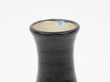 a black vase that is sitting on a white surface