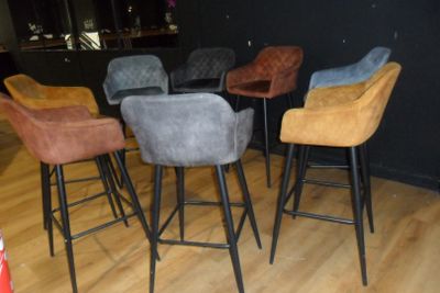 four different colored barstools sitting on a wooden floor