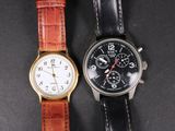 two watches sitting next to each other on a black surface