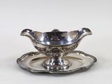 une assiette en argent ancien posée sur une soucoupe, le tout sur un fond blanc