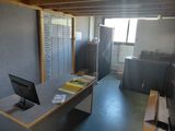 un ordinateur posé sur un bureau, dans une pièce où s'entassent de nombreux papiers