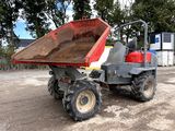 un camion-benne rouge garé sur un terrain en terre battue