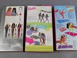 two boxes of barbie dolls sitting on top of a table