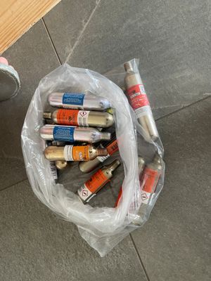a bag of paint and a can of paint next to a trash can