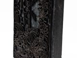 an old black book with intricate designs on it on a white surface