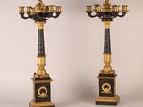 pair of black and gold candelabs with candles on pedestals