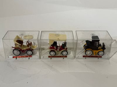 trois petites voitures miniatures dans une boîte transparente posée sur une surface blanche
