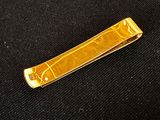 gold plated tie bar on black cloth with a gold design